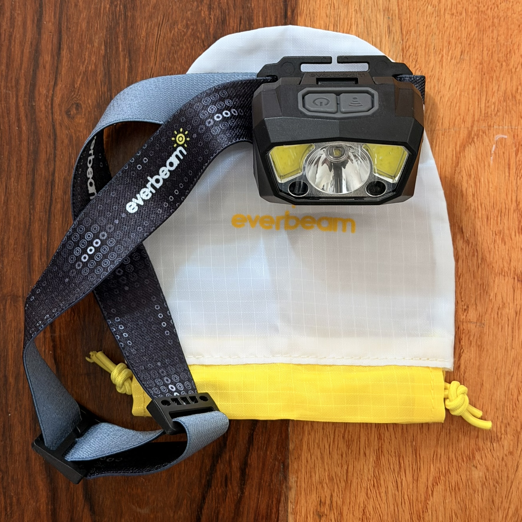 Everbeam H7 Stirnlampe mit Transportbeutel auf Holzhintergrund